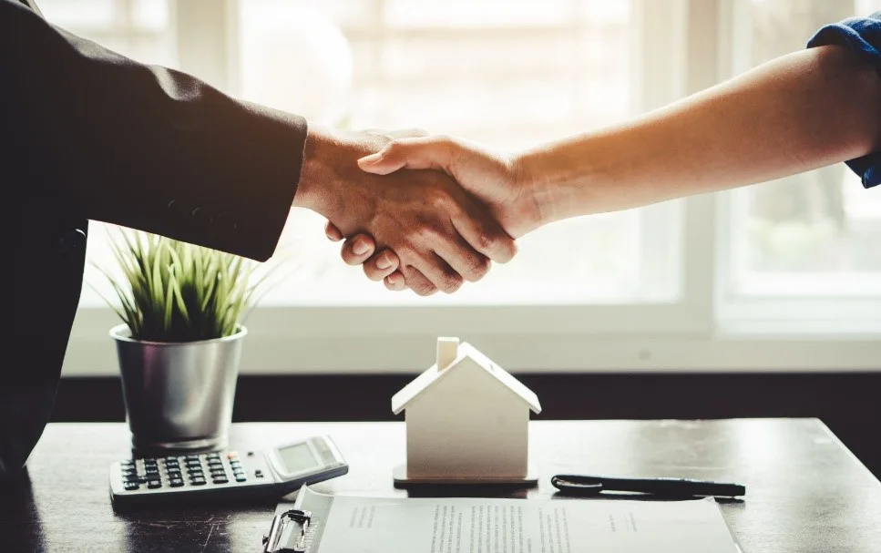 A property transaction represented by a handshake, house model and keys